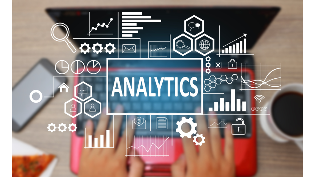 赤いノートパソコンを操作している人の上にANALYTICSの文字と沢山のアイコンやグラフが浮かび上がっている画像