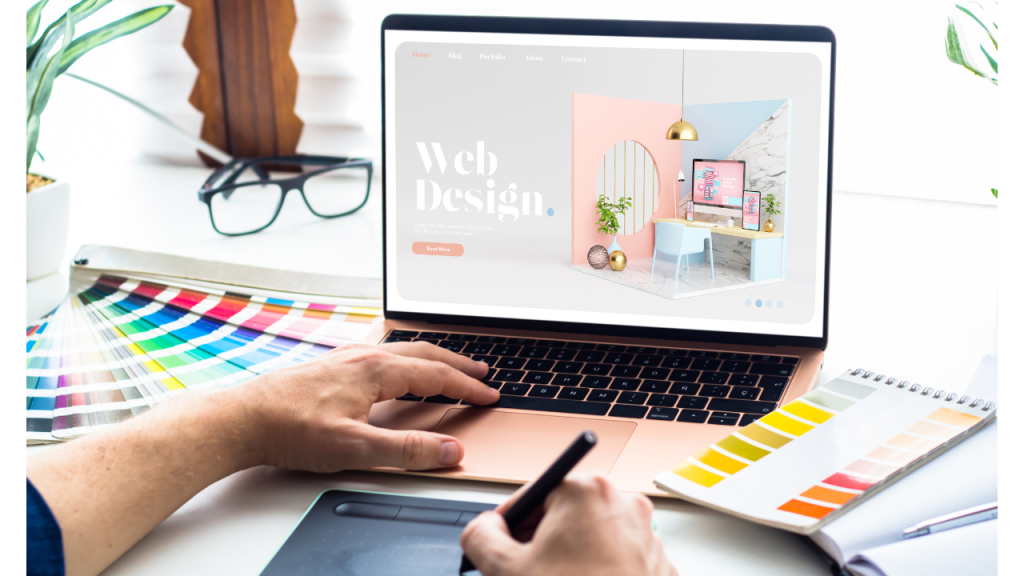 ノートパソコンを操作している人がいて、画面にはWeb Designの文字とパステルカラーの小さな部屋や家具が描かれている写真