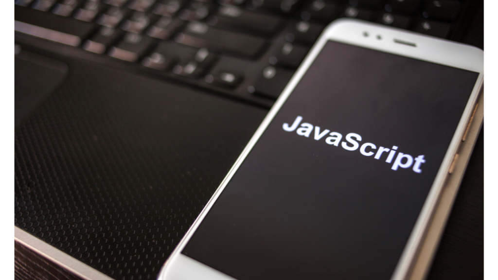 ジャバスクリプトという文字が表示されたスマートフォンがPCの上に置かれている画像