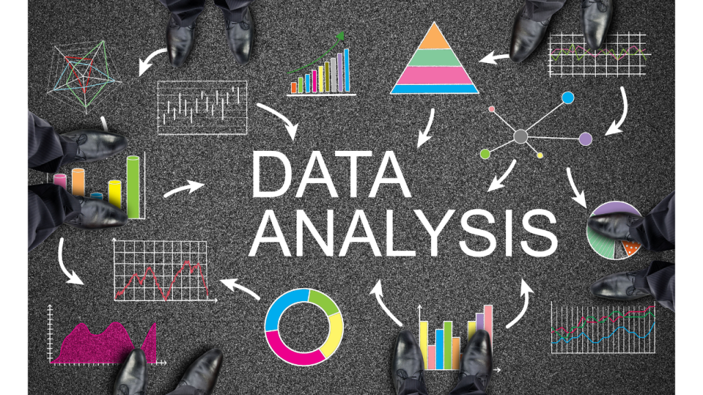 「DATA ANALISIS」（データ分析）と書かれている地面。その周りには棒グラフや折れ線グラフ、円グラフなどがカラフルに書かれている。それを眺めるように立っているビジネスパーソンの足元